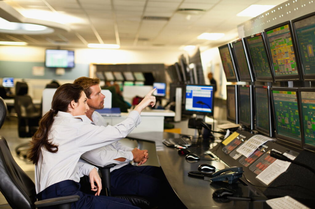 Two people sitting in a room, using Kramer Control solution, powered by KDS-100