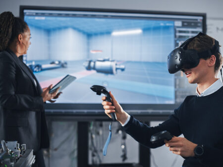 A person wearing VR device, while a woman looks at a wall screen, using Kramer Education solutions