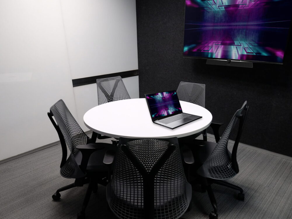 A room with a laptop on a table, and a wall screen, using Kramer's solution for Huddle Rooms