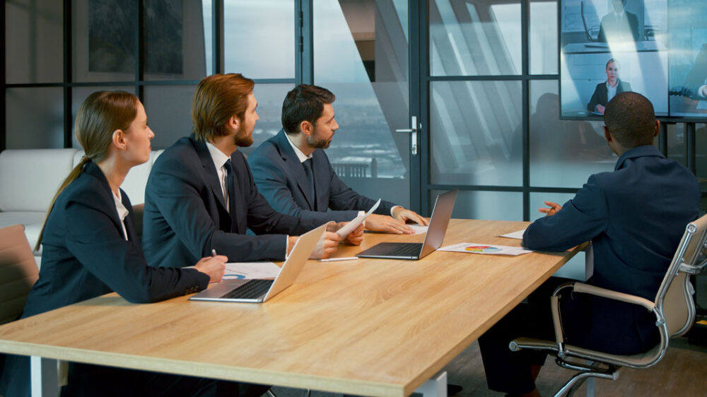 People sitting at a huddle room, using Kramer and Jabra solutions