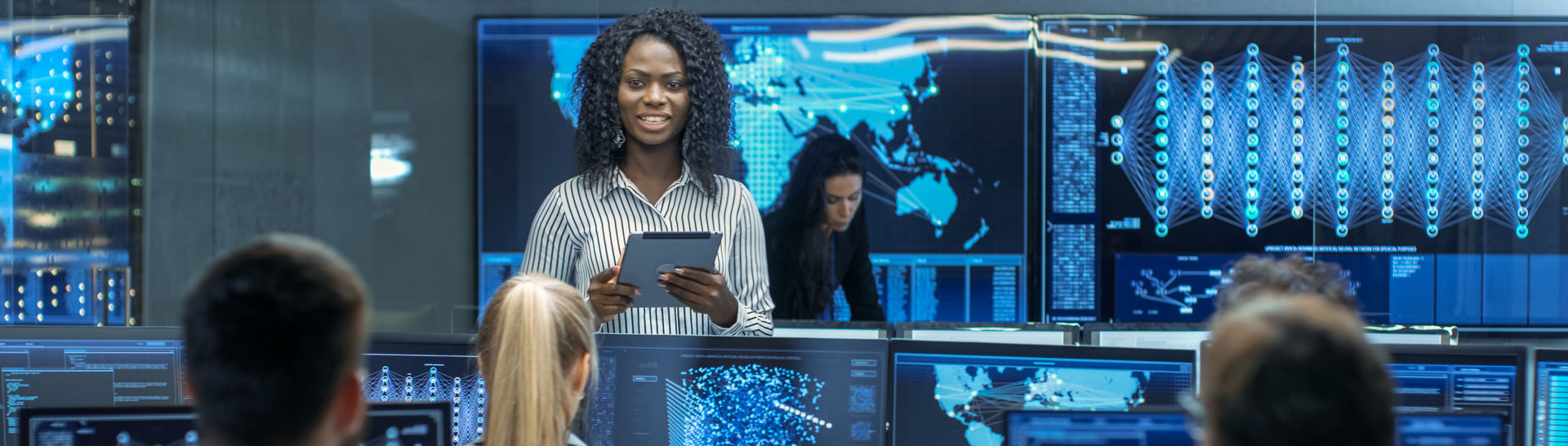 People working at a control room, with a woman displayed on the screen, a place where NETGEAR and Kramer's is installed to provide AVoIP deployment