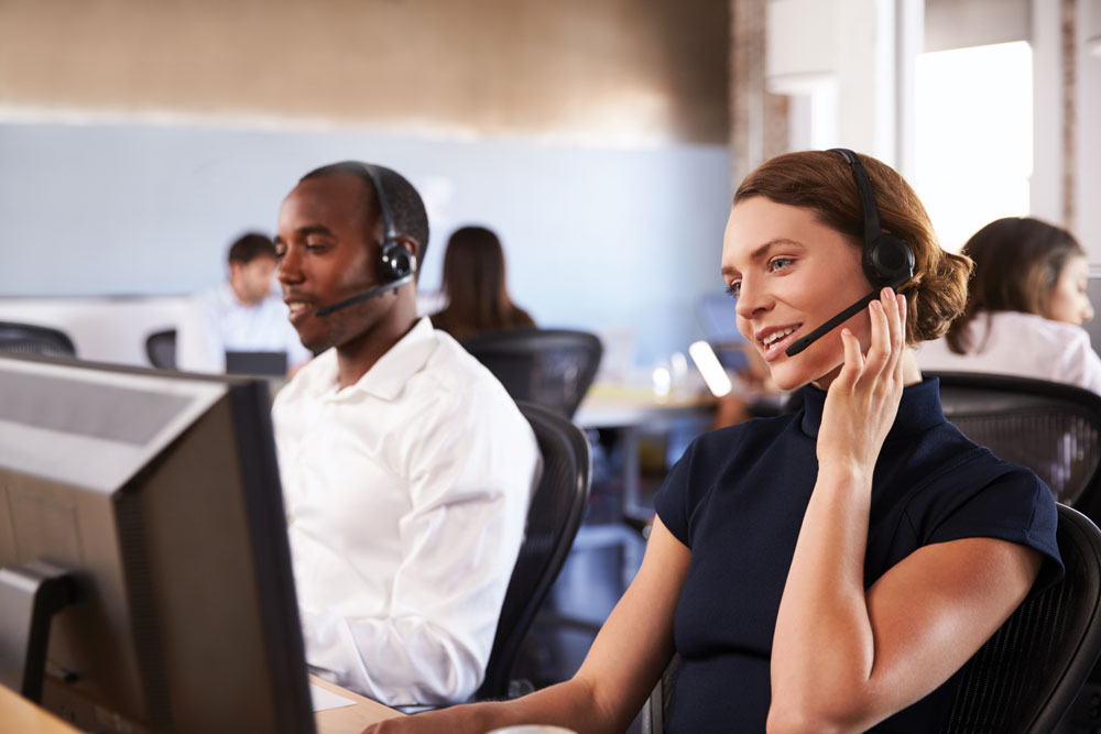 Two people wearing headests, talking, sitting at a support center dedicated for Kramer services