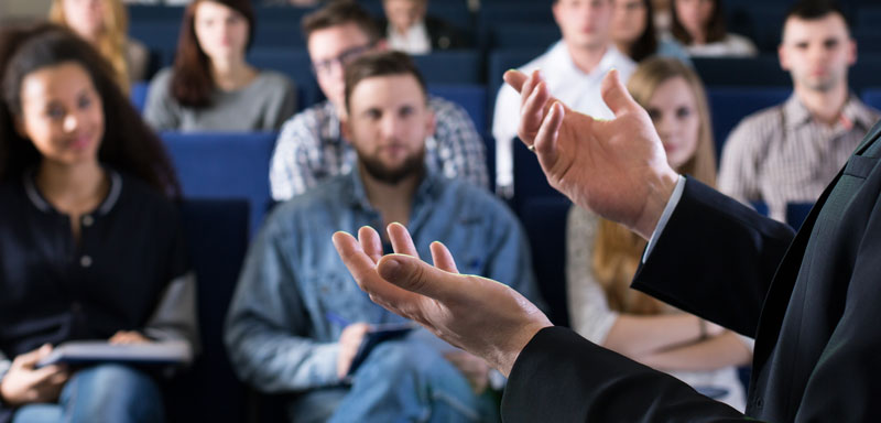 A professor standing in an auditorium, teaching to students, using Kramer Control and Sony Edge solution - One Stop Teaching Studio