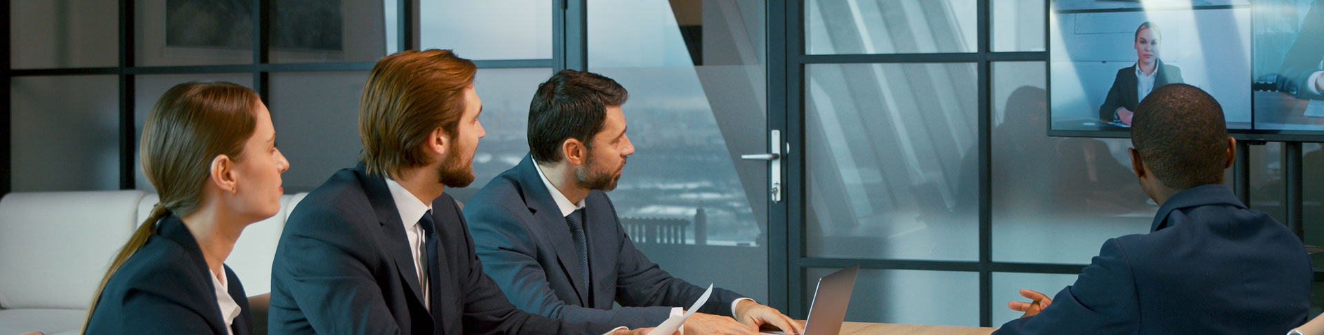 People sitting at a huddle room, using Kramer and Jabra solutions