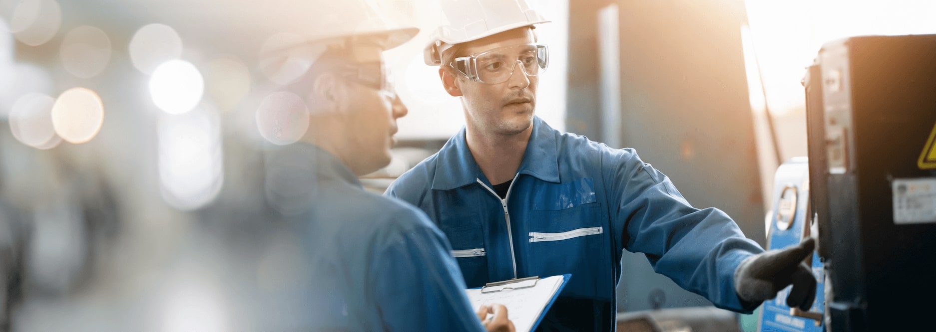 Two people in a work environment, wearing helmets