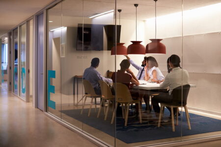 IT Leads, sitting in a glass huddle room, using Kramer's solutions