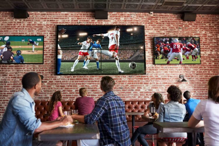 People sitting in an eBar, watching sports on TV screens