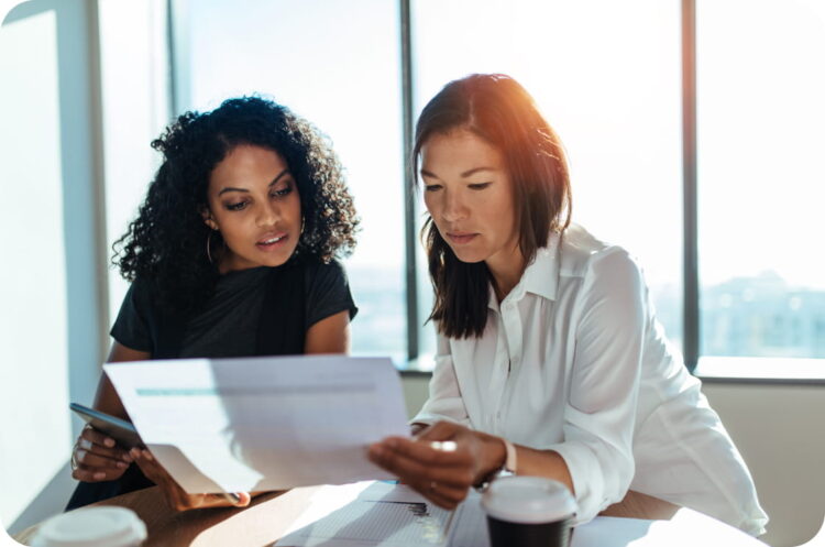 Two women sitting and reading a business document