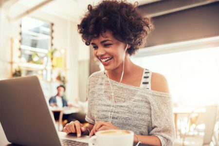 A woman smiling, looking at her computer, working at Kramer