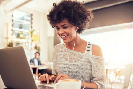 A woman smiling, looking at her computer, working at Kramer