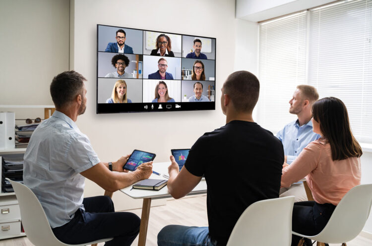 People in a meeting room, talking with remote participants on the screen