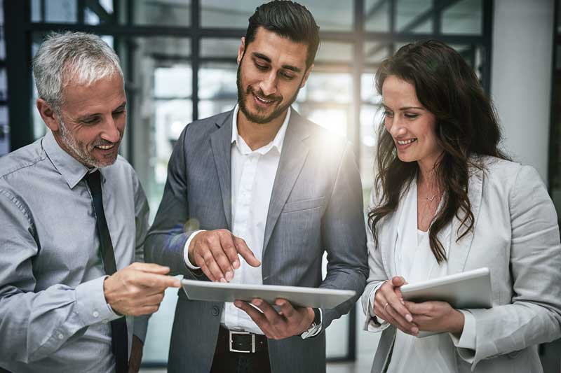 Three business people, standing, talking. and working