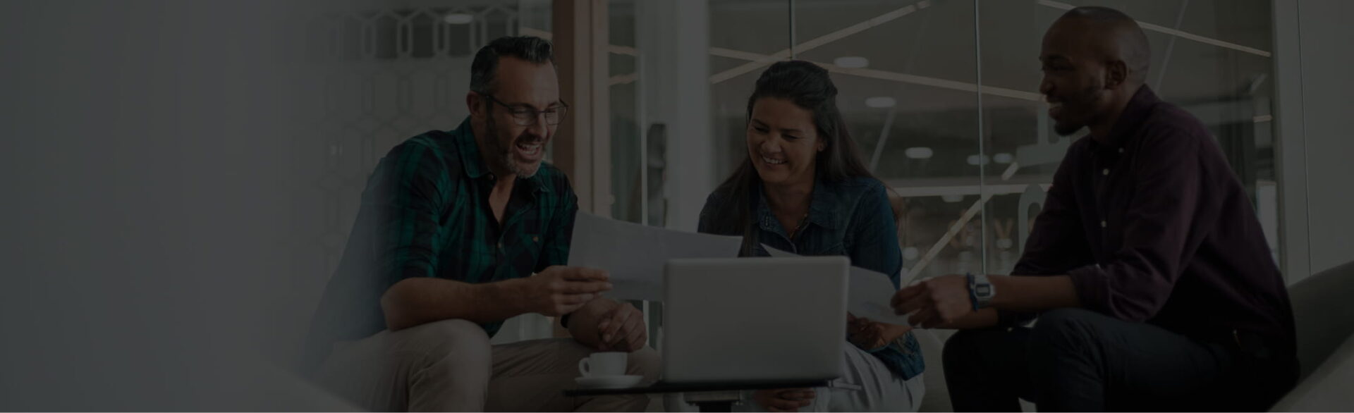 Three people sitting in an office, talking and working