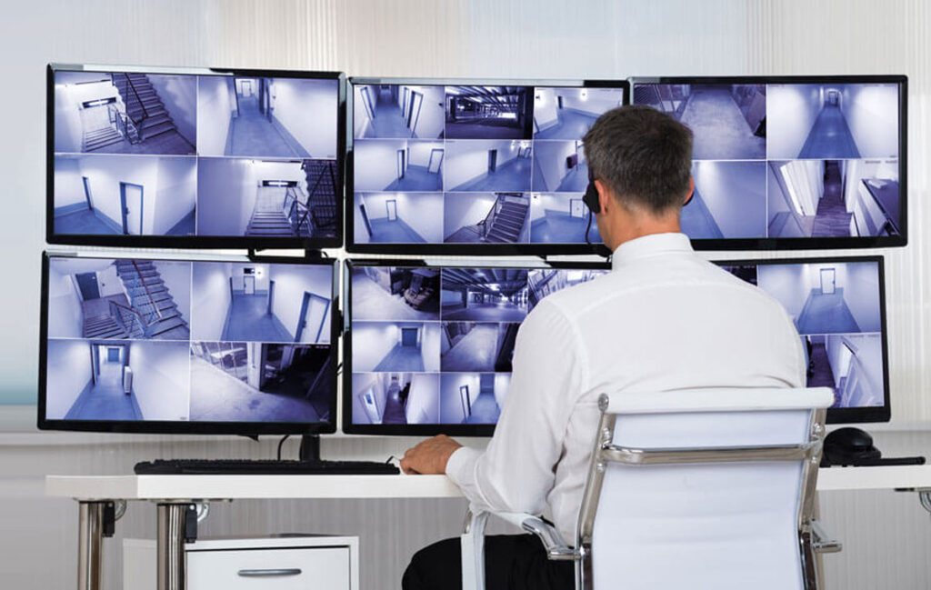 A man looking at multiple screens at a control room, using Kramer's KDS-7 AVoIP streaming solution