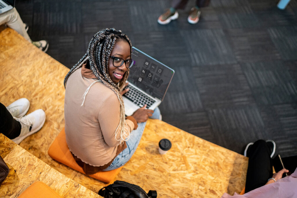 A woman sitting with a computer, smiling at the camera