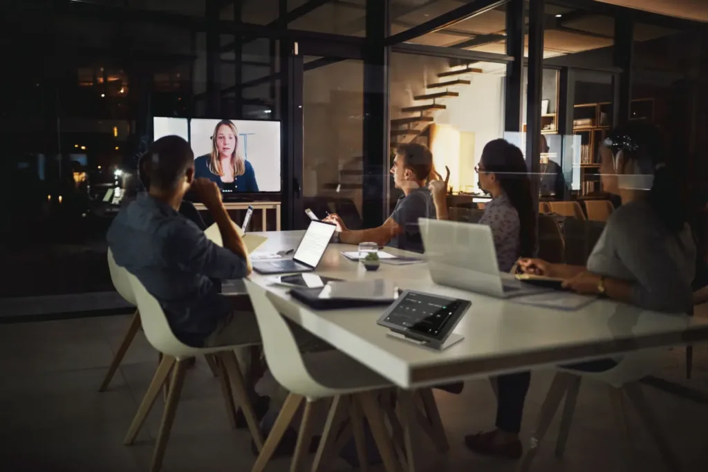 People sitting in a medium meeting room, in a hybrid meeting, using Kramer's solutions for meeting rooms