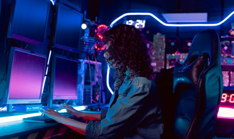 A woman sitting in front of a couple of computer screens in a control center, powered by KDS-17
