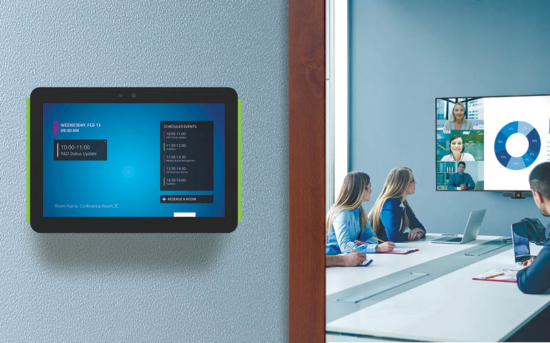 A mounted scheduler on the left, and people sitting in a hybrid meeting room on the right